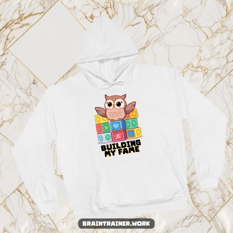 Funny kawaii owl balancing a tall stack of colorful learning blocks, featured on a cozy hoodie for playful learning humor.